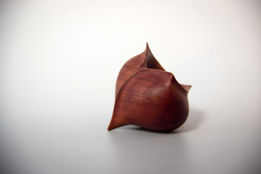 Vue de profil de la sculpture tournée : "Graine d'Amour" (Graine creusée en forme de coeur, en pommier teintée) - Création originale de Coralie Saramago