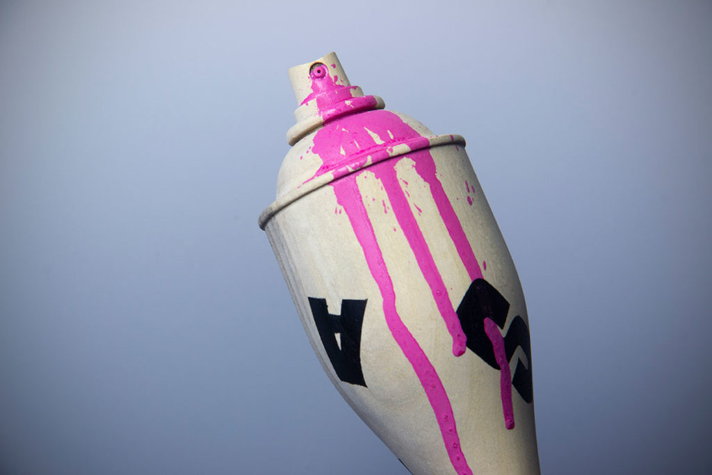 Vue détaillée du haut de la bombe de peinture en bois (micocoulier) recouverte d'un graph de l'artiste supaone nommée chewingcan. oeuvre collaborative avec l'artiste coralie saramago